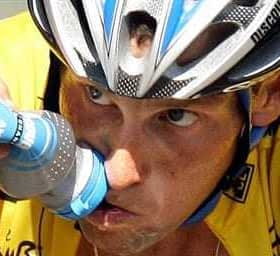 Cyclist in a yellow jersey drinking from a water bottle during a race. - Olive Oil Times