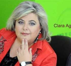 Portrait of Clara Aguilera with a green background, wearing a red jacket and a watch. - Olive Oil Times
