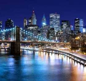 Night view of the Brooklyn Bridge with the Manhattan skyline illuminated in the background. - Olive Oil Times