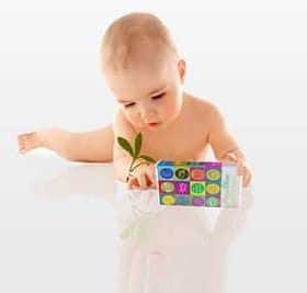 Infant exploring a colorful toy with numbers and letters while holding a small plant. - Olive Oil Times