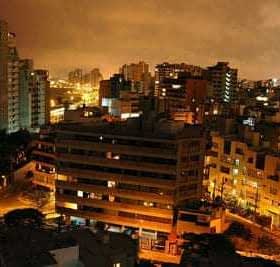 A nighttime view of Lima, Peru, showcasing buildings and city lights under a cloudy sky. - Olive Oil Times