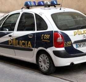 A Spanish police car with blue lights and 'Policía' written on the side parked on a street. - Olive Oil Times