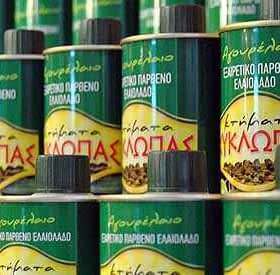 Row of green cans of Kyklopas extra virgin olive oil with yellow labels and Greek text. - Olive Oil Times