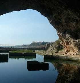 View of a cave opening with water reflecting the surrounding rock formations. - Olive Oil Times