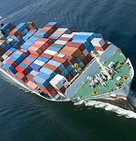 Aerial view of a cargo ship loaded with colorful shipping containers on water. - Olive Oil Times