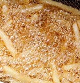 Fried potato strips bubbling in hot oil during the cooking process. - Olive Oil Times