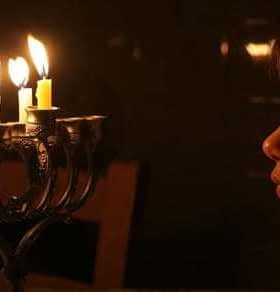 A child gazing at a menorah with lit candles during a celebration. - Olive Oil Times