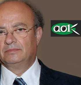 A portrait of a middle-aged man with glasses, wearing a suit and tie, against a neutral background. - Olive Oil Times