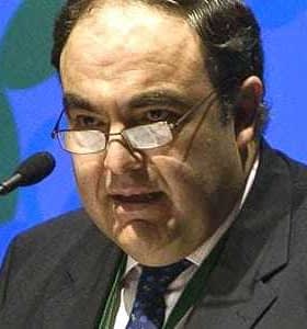 A man wearing glasses speaking at a podium during a conference or event. - Olive Oil Times