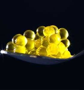 A spoon holding yellow caviar pearls arranged in a clustered formation. - Olive Oil Times