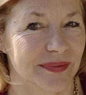 Close-up portrait of a woman with light hair and subtle makeup, smiling softly at the camera. - Olive Oil Times