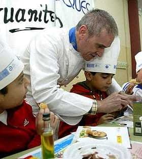 Chef demonstrating cooking techniques to children wearing chef hats at a table. - Olive Oil Times