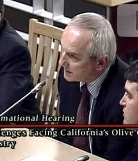 Three men seated at a table during an informational hearing about California's olive oil industry. - Olive Oil Times