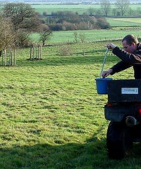 Individual on an ATV pouring material from a bucket while in a grassy field. - Olive Oil Times