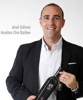 José Gálvez holding a bottle of Oro Bailen olive oil while wearing a black blazer and white shirt. - Olive Oil Times