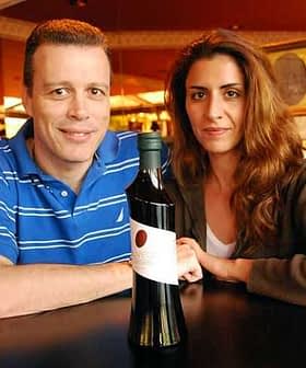 Two individuals, a man and a woman, posing with a bottle of olive oil in a restaurant setting. - Olive Oil Times