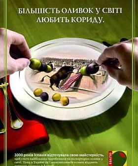 Hands holding a plate with olives and an illustration of a bullfight scene. - Olive Oil Times