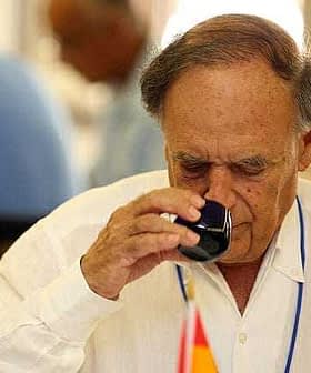 An older man in a white shirt tasting olive oil from a small glass cup. - Olive Oil Times