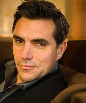 Close-up portrait of a man with dark hair wearing a suit, seated on a couch. - Olive Oil Times