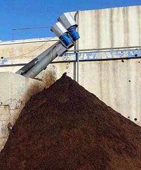 Large pile of olive pomace at an olive oil processing facility with a conveyor system. - Olive Oil Times
