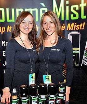 Two women posing with Gourmè Mist products at a promotional event. - Olive Oil Times