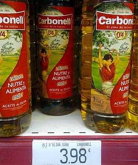 Three bottles of Carbonell olive oil displayed on a store shelf with a price tag below. - Olive Oil Times