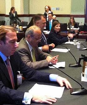 A group of individuals seated at a conference table during a meeting in a formal setting. - Olive Oil Times
