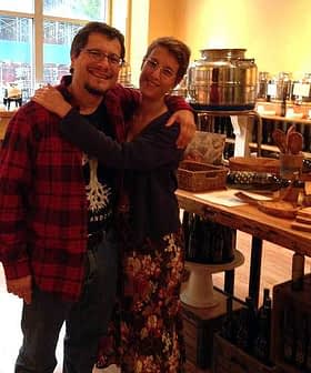 A man and woman smiling while embracing each other in a store setting with various items in the background. - Olive Oil Times