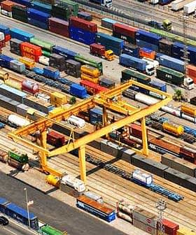 Aerial view of a cargo container terminal with various shipping containers and cranes. - Olive Oil Times