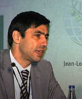 Jean-Louis Barjol speaking at a conference with a logo in the background. - Olive Oil Times