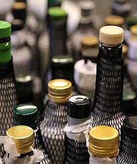 A variety of olive oil bottles with different colored caps and labels arranged closely together. - Olive Oil Times