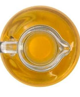 A glass cruet filled with yellow olive oil viewed from above. - Olive Oil Times