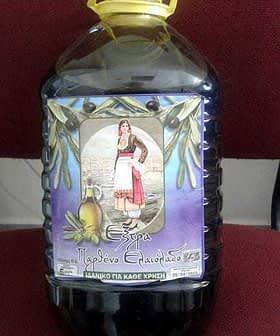 Plastic bottle of extra virgin olive oil with a label featuring a traditional Greek woman. - Olive Oil Times