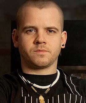 Man with short hair wearing an apron and necklace, looking directly at the camera. - Olive Oil Times