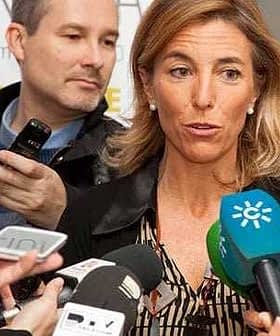 A woman speaking to reporters while multiple microphones are directed towards her. - Olive Oil Times