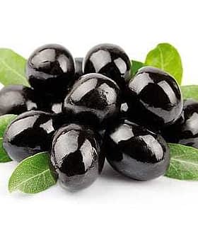 A cluster of black olives resting on green leaves, showcasing their glossy surface. - Olive Oil Times