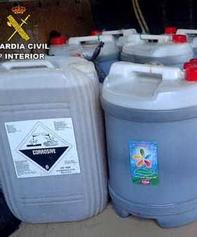 Several containers labeled as corrosive substance, stacked together with a warning symbol. - Olive Oil Times