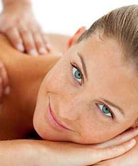 A woman with blue eyes and light brown hair lying on a massage table during a massage session. - Olive Oil Times