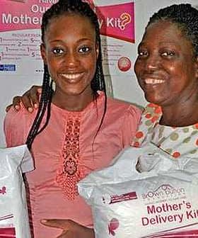 Two women smiling while holding Mother's Delivery Kits in their hands. - Olive Oil Times