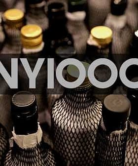 Multiple bottles with dark netting and various colored caps arranged closely together. - Olive Oil Times