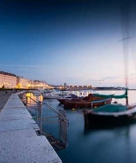 Several boats docked at a harbor with calm water during twilight hours. - Olive Oil Times