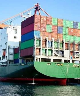 Large container ship loaded with colorful shipping containers at a dock. - Olive Oil Times