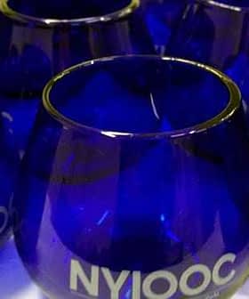 Set of cobalt blue glasses featuring the NYIOOC logo on the front. - Olive Oil Times