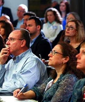 A diverse group of individuals attentively listening during a conference presentation. - Olive Oil Times