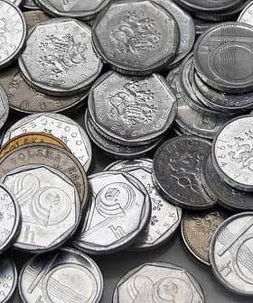 A collection of various Czech coins arranged in a disordered pile on a flat surface. - Olive Oil Times