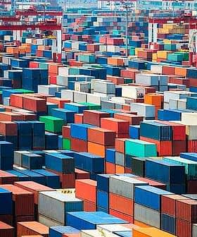 Aerial view of numerous shipping containers stacked in various colors at a port facility. - Olive Oil Times