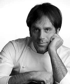 Black and white portrait of a chef resting his chin on his hand, wearing a white chef's uniform. - Olive Oil Times