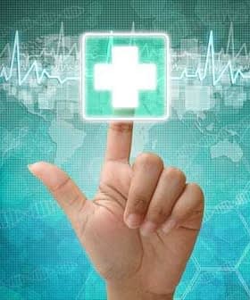 A hand pointing at a digital health icon featuring a medical cross on a blue background. - Olive Oil Times