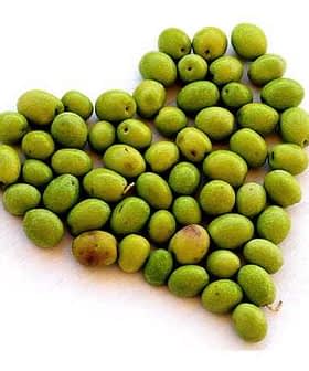 A collection of green olives arranged in the shape of a heart on a white background. - Olive Oil Times