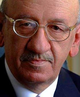 Close-up portrait of an older man wearing glasses and a suit with a serious expression. - Olive Oil Times